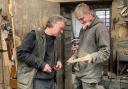 Master wheelwright Nick Gill and newly-qualified wheelwright Ted Shepherd look at a spoke before sanding.