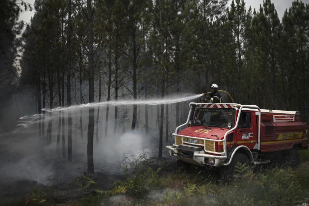 Forestry Journal: A firefighter sprays water as smoke rises at a forest fire near Louchats, 35 kms (22 miles) from Landiras in Gironde, southwestern France,